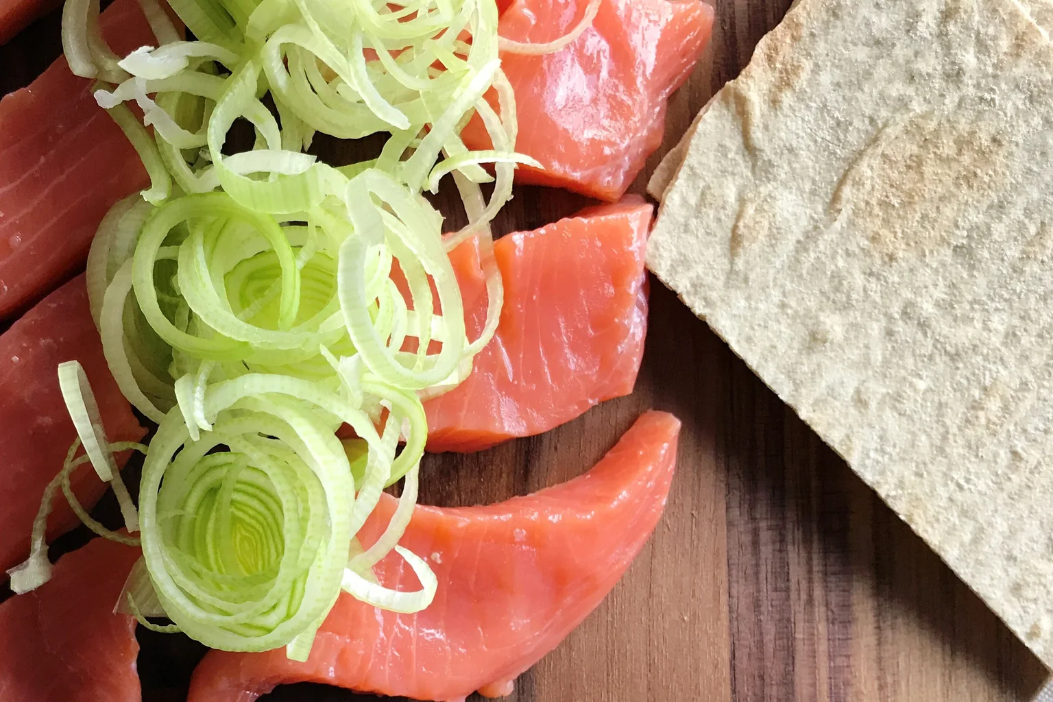 Purre i tynne ringer og en potetlefse ved siden av rakfiskskivene på trefjøla